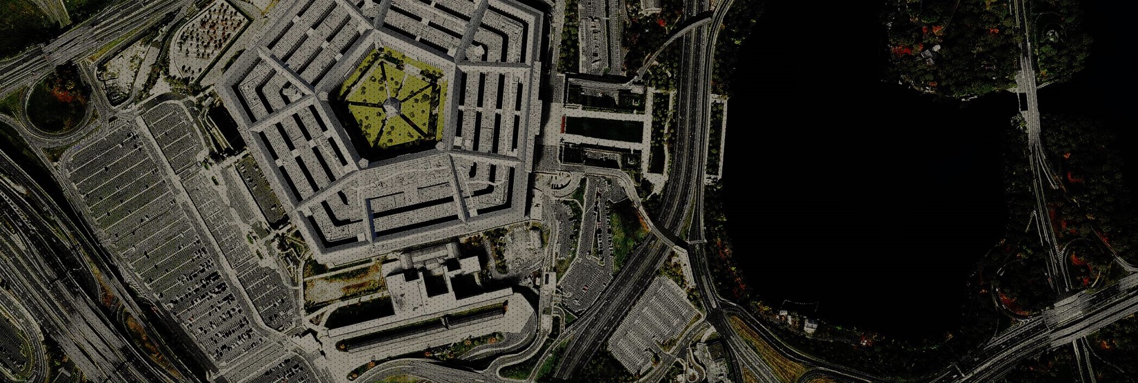 Eine Luftaufnahme des Pentagon-Gebäudes, der umliegenden Straßen und eines großen Gewässers zu seiner Rechten.