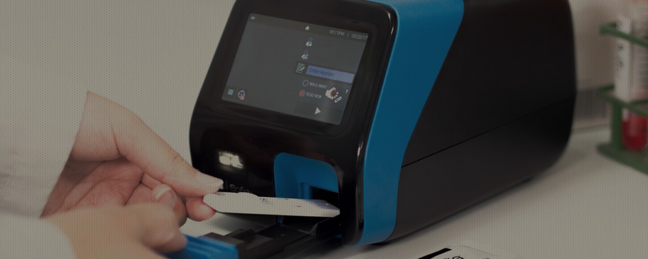 A close-up of a hand inserting a test sample into the Immunoassay Analyzer