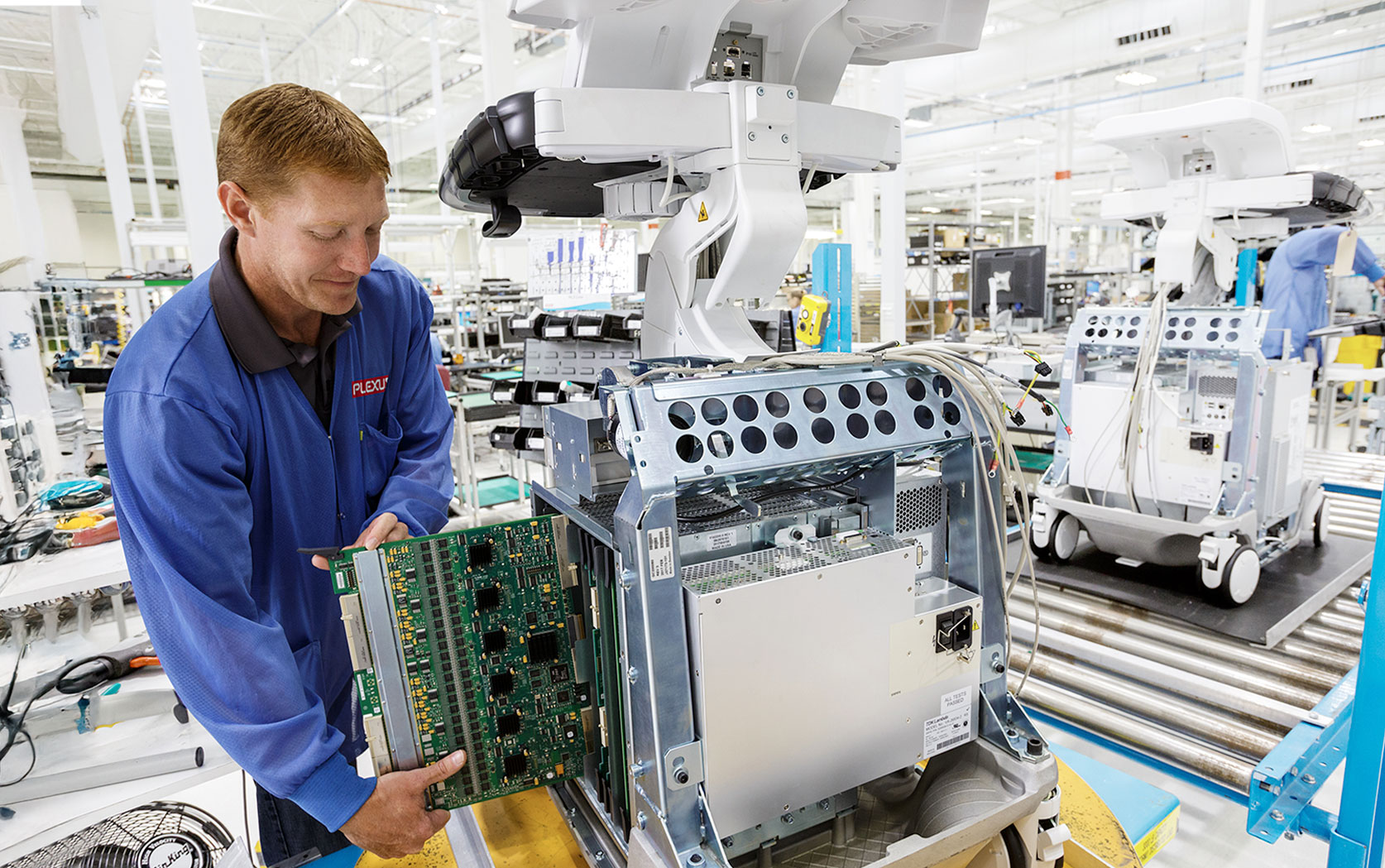 A member of the Plexus team carefully removing an internal printed circuit board assembly from a medical ultrasound machine.